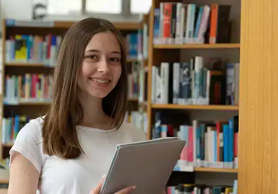 a young female college student standing in a library