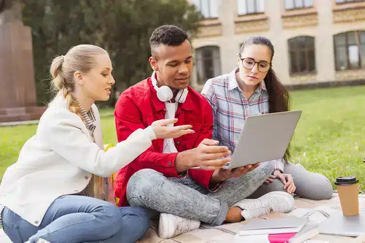 college students discussing online business program sitting on the grass