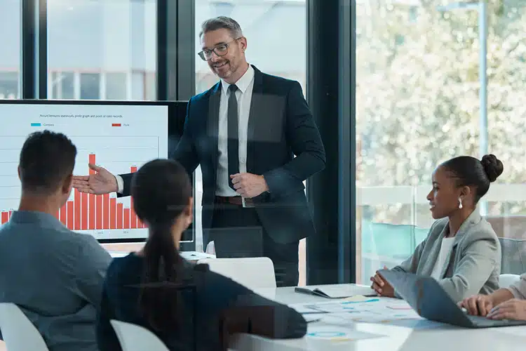 a male CEO presenting stats to his team