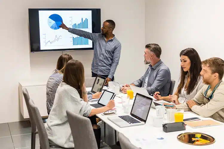 a male corporate employee presenting relevant data to his colleagues