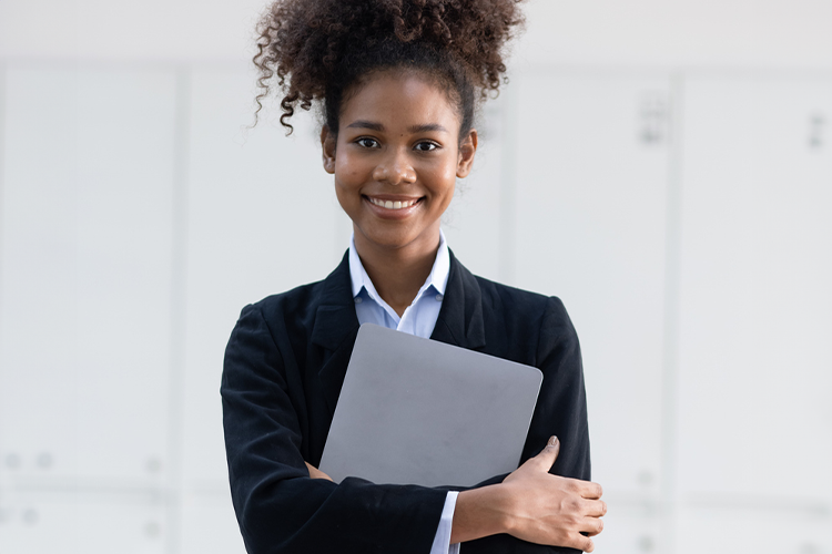 a female college student holding a notebook and posing for the camera