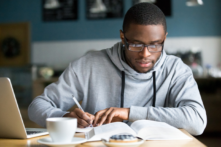 a male associate degree student working at his study desk