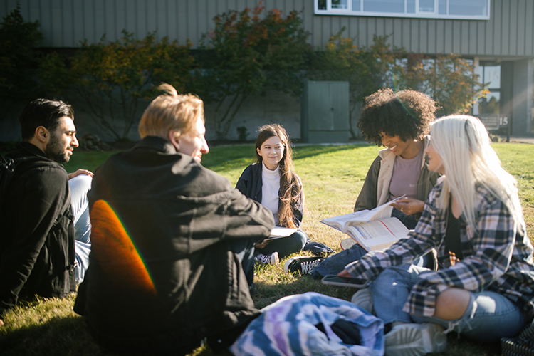 community college students sitting on the campus lawn