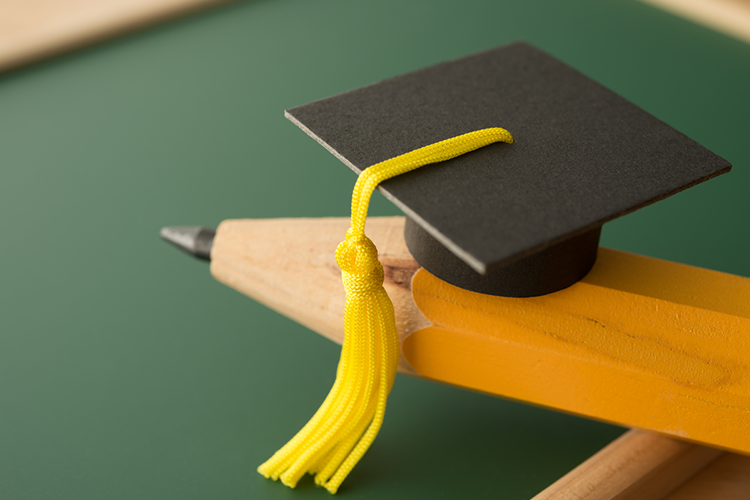 a small graduation cap placed on a large pencil