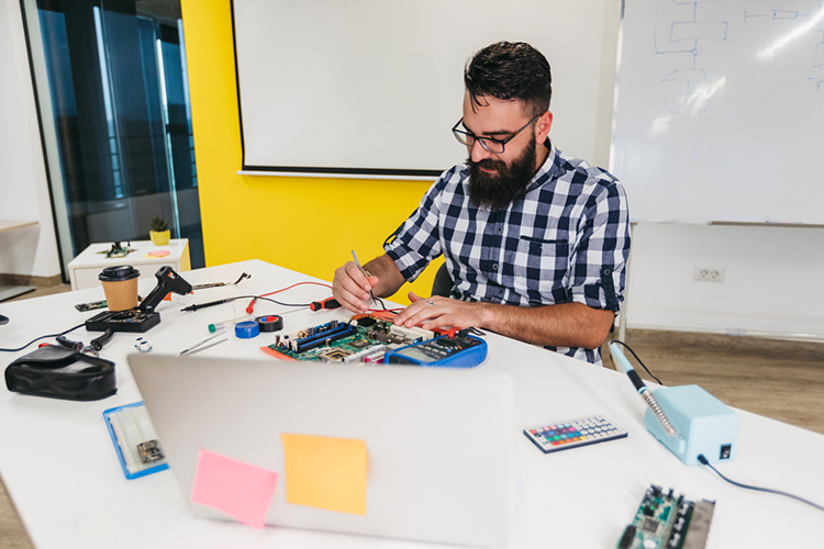 a male online college student tinkering with his engineering tools